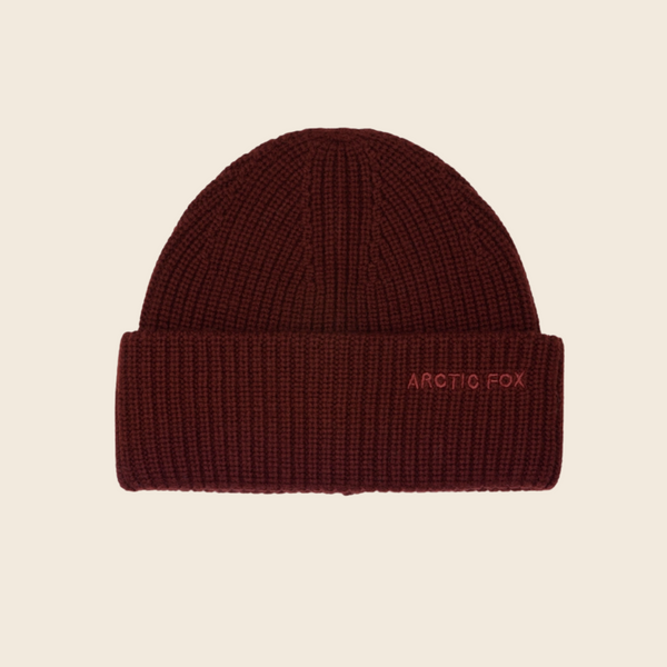 Brown knit beanie with 'Arctic Fox' embroidery on a beige background