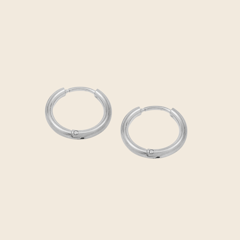 Pair of silver hoop earrings on a beige background