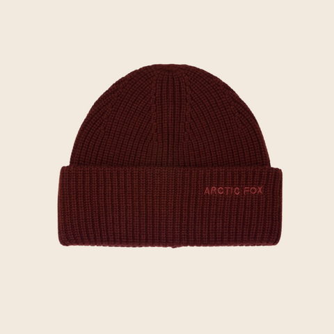 Brown knit beanie with 'Arctic Fox' embroidery on a beige background