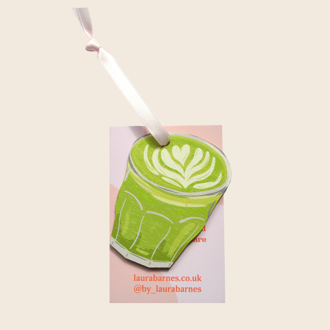 Card with a green latte art design and a white candle on a beige background, featuring the brand 'laurabarnes.co.uk'.