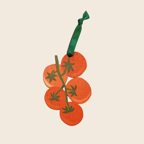 Decorative ornament shaped like a branch of tomatoes with a green ribbon on a beige background