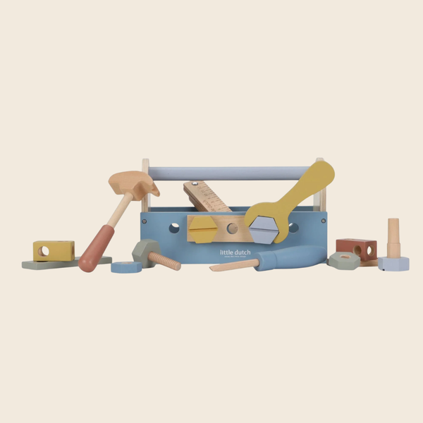 Little Dutch wooden toy toolbox set with assorted hand tools including a hammer, wrench, screwdriver, and blocks, displayed on a solid light beige background.