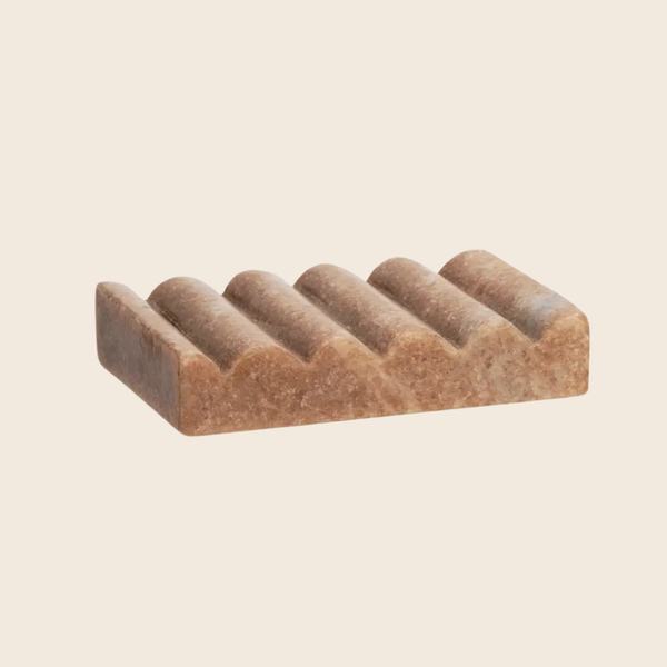 A rectangular soap dish with a wavy, ribbed texture in a warm brownish-beige color, shown on a solid light beige background.