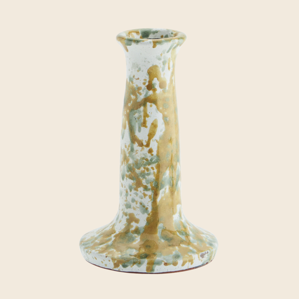 Decorative ceramic candle holder with gold and green marbled pattern on a beige background