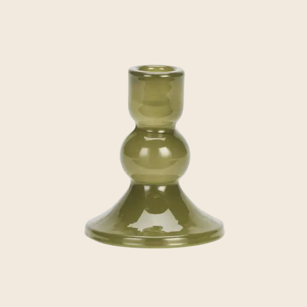 An olive green glass candlestick holder with a bulbous middle section and a flared base, shown on a solid light beige background.