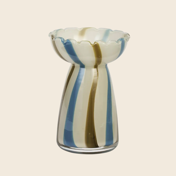 A hand-blown glass vase with a scalloped rim, featuring vertical stripes of blue, olive green, and cream on a clear glass base, set against a solid light beige background.