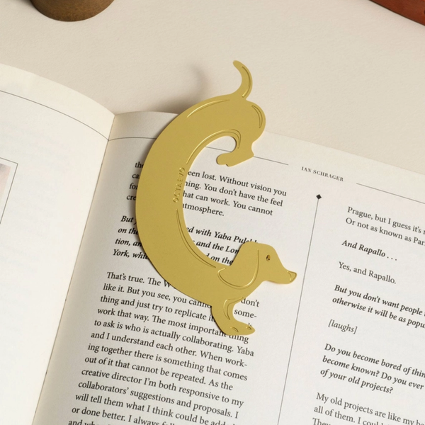 A gold sausage dog bookmark, resting on open book pages.