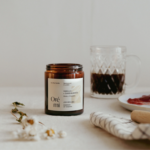 Oré mi candle with a mug of coffee and cookies on a table