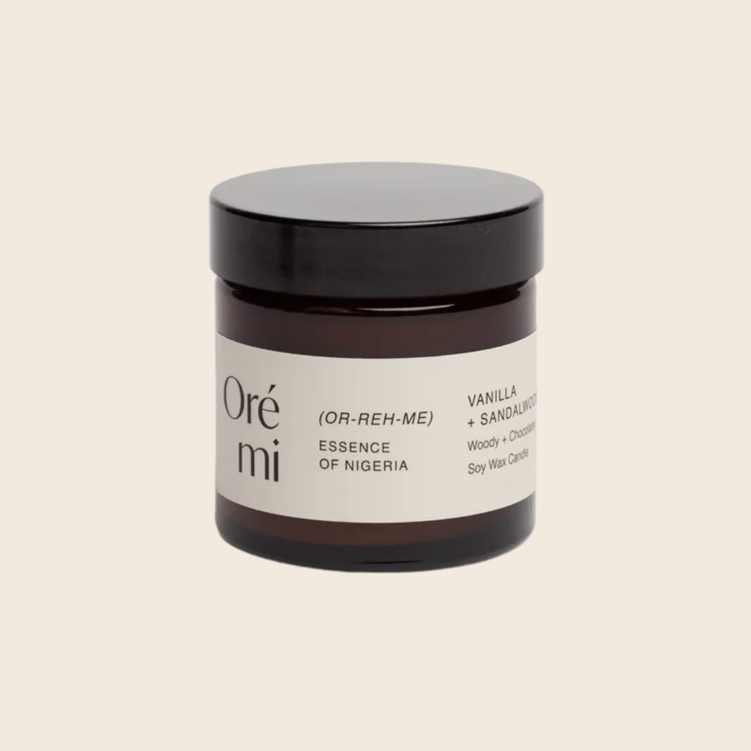 Jar of Ore Mi candle with black lid on a beige background