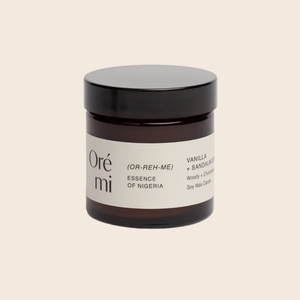 Jar of Ore Mi candle with black lid on a beige background