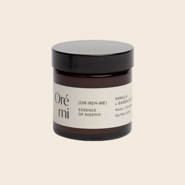 Jar of Ore Mi candle with black lid on a beige background