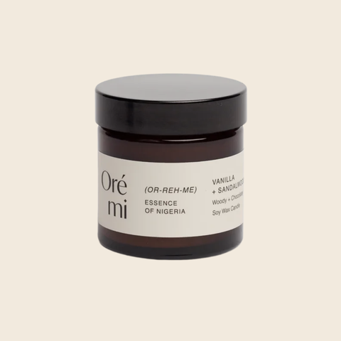 Jar of Ore Mi candle with black lid on a beige background
