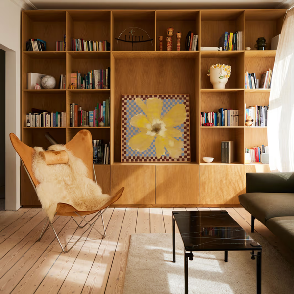 Modern living room with wooden bookshelf, chair, and coffee table.