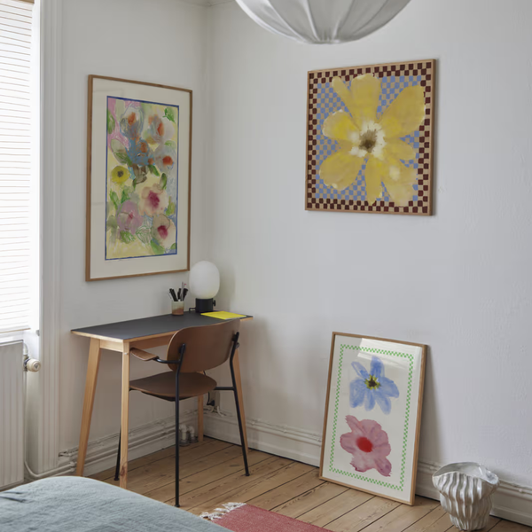 Small home office with a desk, chair, and floral artwork on the wall.