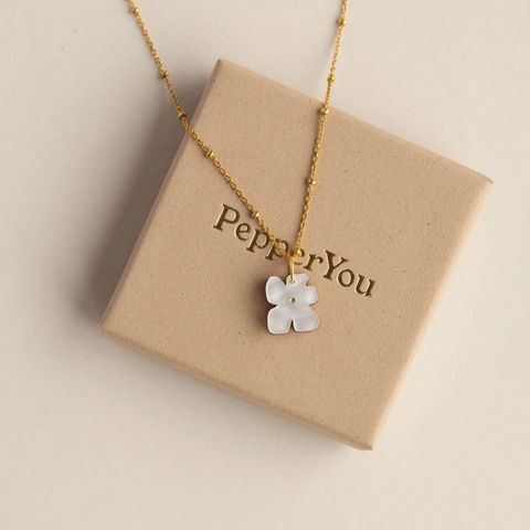 Necklace with a white flower pendant on a 'PepperYou' branded box.