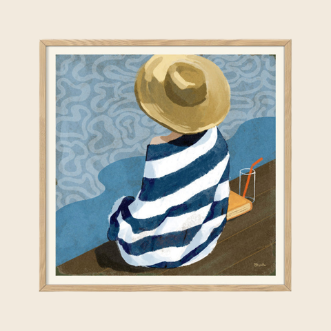 Framed artwork of a person wrapped in a blue and white striped towel, wearing a straw hat, sitting on a bench.
