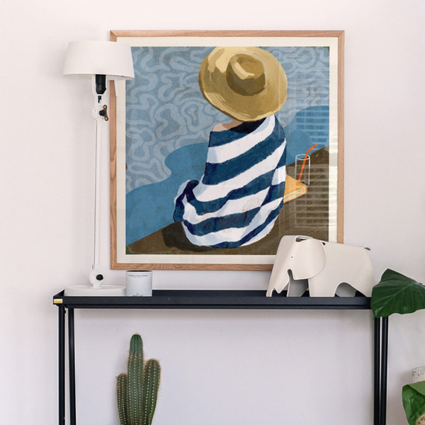 Framed artwork of a person in a striped dress and hat on a shelf with decorative items.