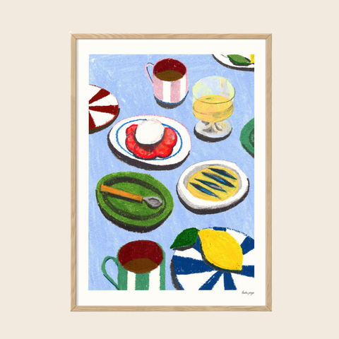 Framed artwork of colorful still life with plates, cups, and a lemon on a blue background.