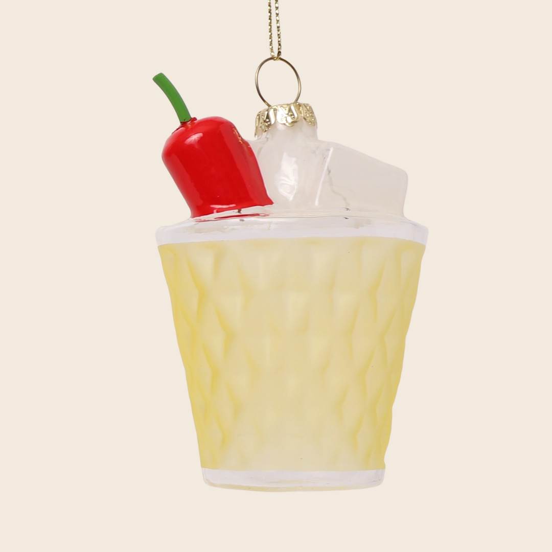 Decorative ornament shaped like a margarita cocktail with a red chilli pepper on top, hanging against a beige background.