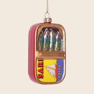 Decorative ornament shaped like a can of sardines on a beige background.