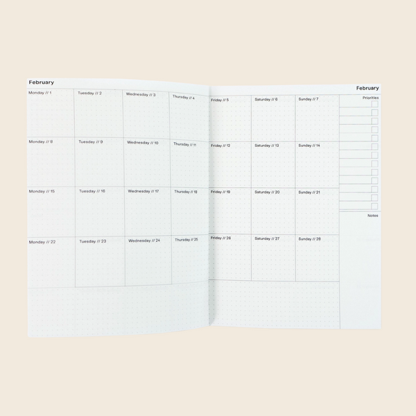 A monthly planner spread showing the month of February with daily boxes from Monday to Sunday and a prominent priority checklist column on the right, photographed on a solid light beige background.